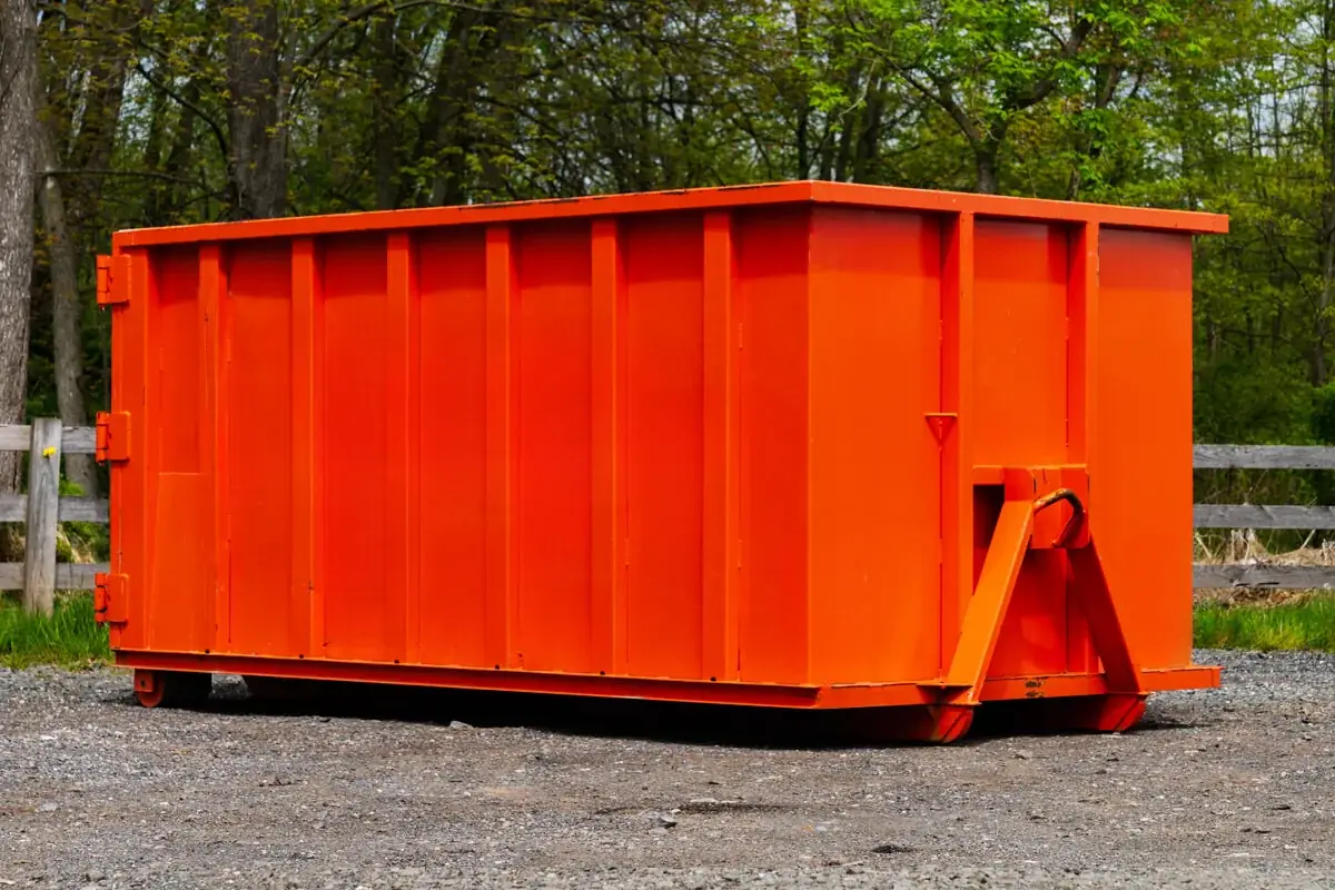Orange roll-off dumpster on gravel