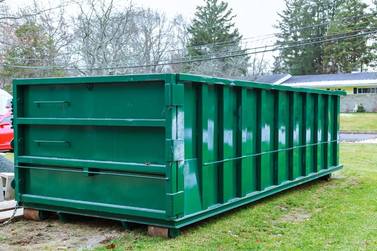 Large green roll-off dumpster at a landscaping project