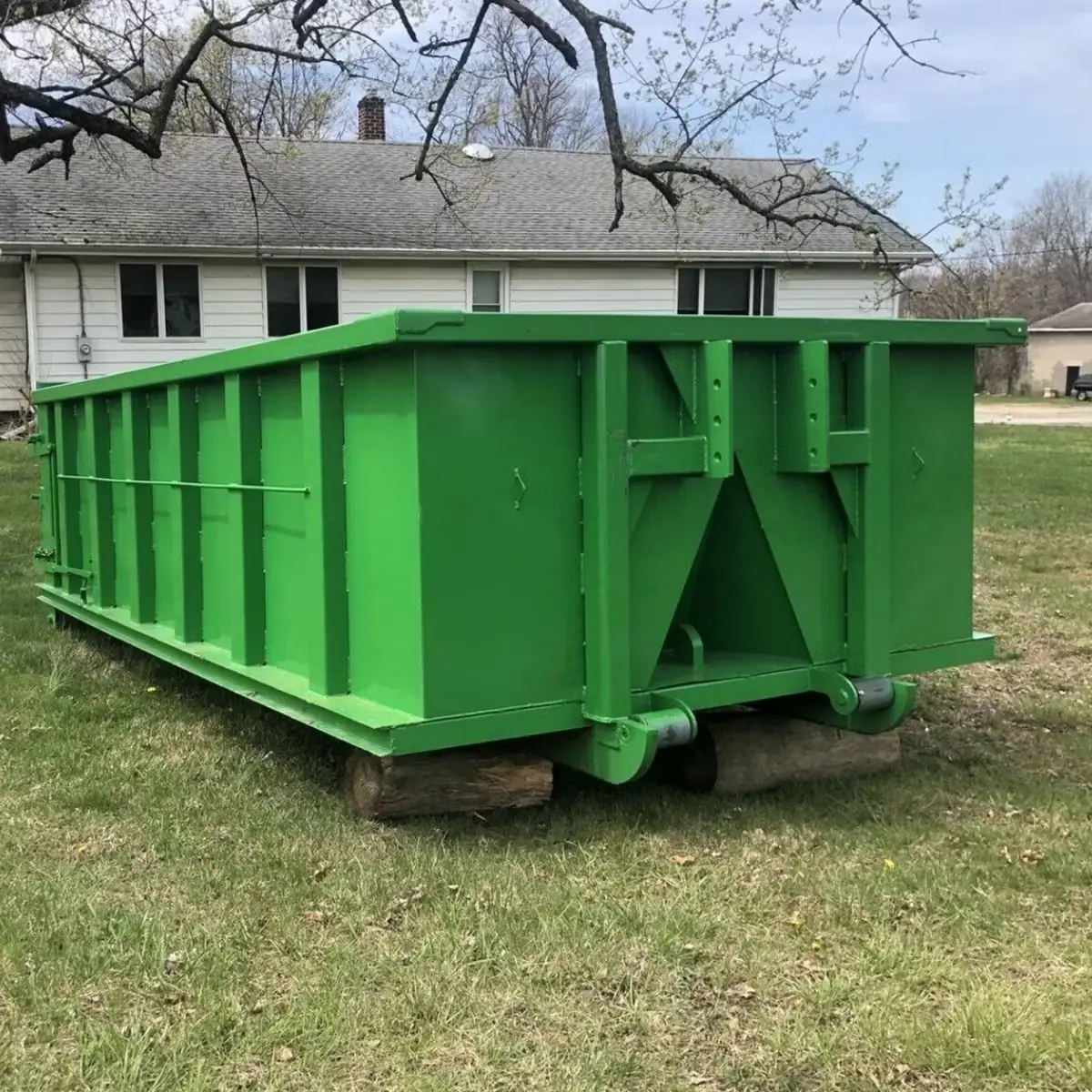 Roll-off dumpster resting on wood boards