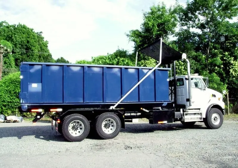 Roll-off truck hauling a tarped dumpster